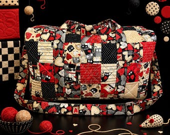 May include: A quilted duffel bag featuring a patchwork pattern of black, red, and cream fabric squares. The design includes illustrations of cats, hearts, and polka dots, with text reading "Life is better with my cat" and "Love my cat".