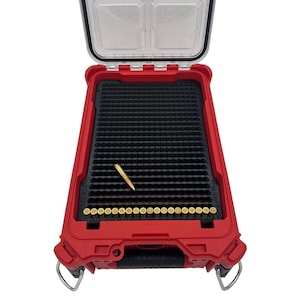 May include: A red, open storage case with a clear lid, holding a black insert with multiple holes. Several gold-colored bullets are visible, with one bullet placed separately. The case has a handle and is designed for ammunition storage.