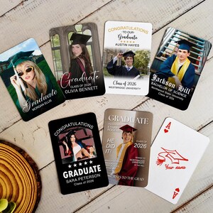 May include: A collection of graduation-themed playing cards featuring photos of graduates. The cards display names, the year 2026, and congratulatory messages. One card is an Ace of Hearts with a graduation cap illustration.