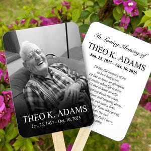 May include: Two memorial fans with wooden handles. One fan features a black and white photo of a smiling older man. The other fan has text that reads "In Loving Memory of THEO K. ADAMS Jan. 25, 1937 - Oct. 10, 2025" and a poem.