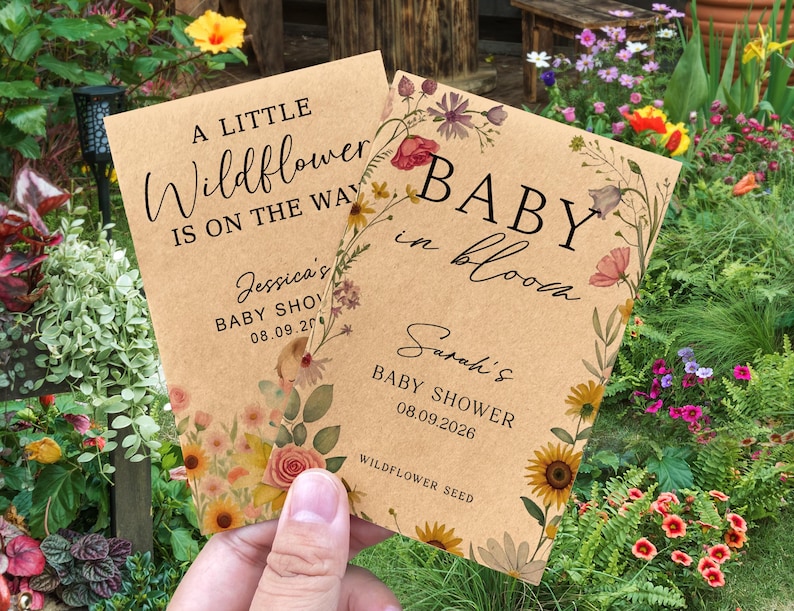 May include: Two kraft paper baby shower announcements with floral designs. One reads "A Little Wildflower Is On The Way," and the other says "Baby In Bloom." Both include baby shower details and wildflower seed information.