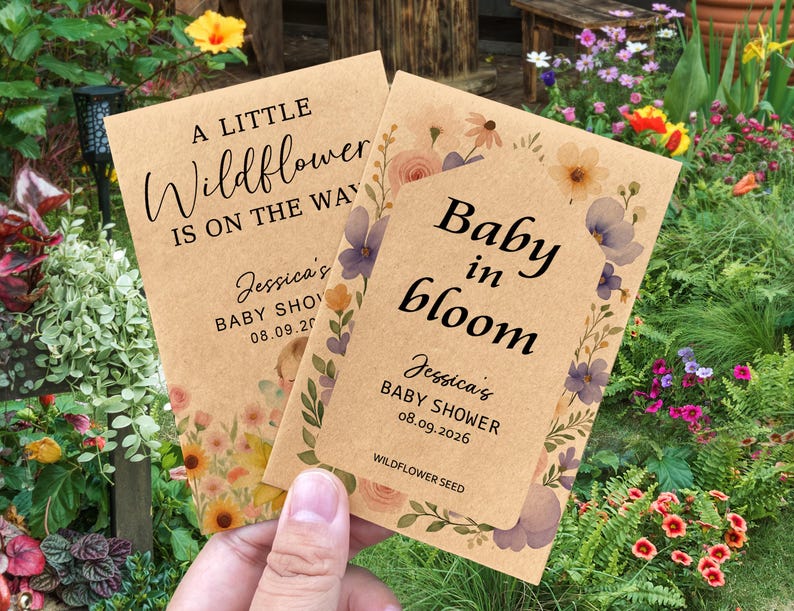 May include: Two kraft paper baby shower seed packets. One reads "A LITTLE Wildflower IS ON THE WAY" and the other says "Baby in bloom". Both packets are decorated with floral designs and include the baby shower details.