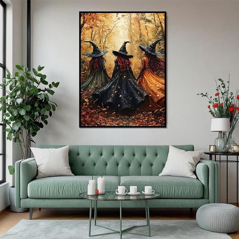 May include: A framed wall art print depicting three figures wearing pointed hats and long flowing cloaks in shades of black, green, and orange, standing in a forest filled with autumn leaves and golden light, presented in a black frame.