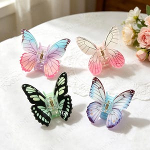 May include: Four butterfly-shaped hair clips in various colors. One clip has pink, purple, and blue wings, another has white and pink wings, a third has black and green wings, and the last has blue and purple wings.