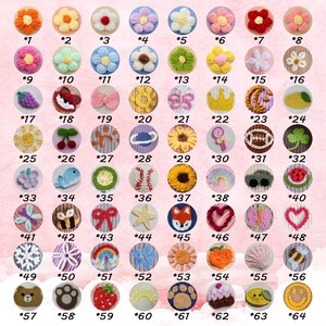 May include: A collection of 64 colorful, handmade crochet buttons with various designs, including flowers, animals, and food items. Each button is numbered and set against a pink background.