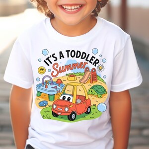 Puede incluir: Camiseta blanca con el texto "IT'S A TODDLER Summer" y un dise&ntilde;o de dibujos animados colorido. El dise&ntilde;o incluye un coche rojo y amarillo, un parque infantil, una tortuga y burbujas. Un ni&ntilde;o lleva la camiseta.