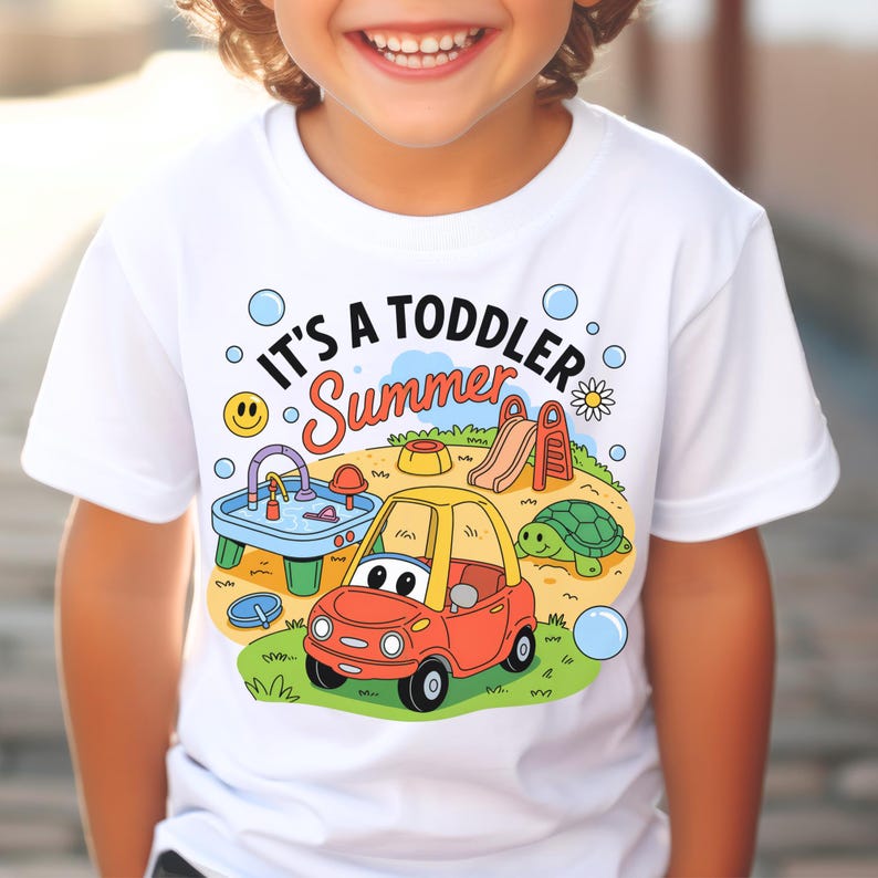 Puede incluir: Camiseta blanca con el texto "IT'S A TODDLER Summer" y un dise&ntilde;o de dibujos animados colorido. El dise&ntilde;o incluye un coche rojo y amarillo, un parque infantil, una tortuga y burbujas. Un ni&ntilde;o lleva la camiseta.