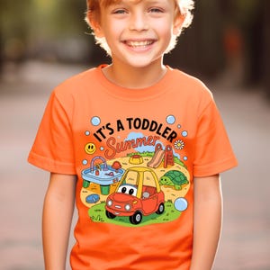 Puede incluir: Camiseta naranja para ni&ntilde;os peque&ntilde;os con el texto "It's a Toddler Summer" y un gr&aacute;fico colorido de un coche, un tobog&aacute;n y una tortuga. La camiseta es de material suave y es adecuada para el clima c&aacute;lido.