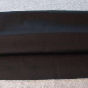 Peut inclure: Un morceau de tissu noir plié, probablement pour l'artisanat ou la couture. Le tissu est de couleur unie et foncée, et semble lisse. L'image comprend le texte "CRAFT supplies by handmade baskets".