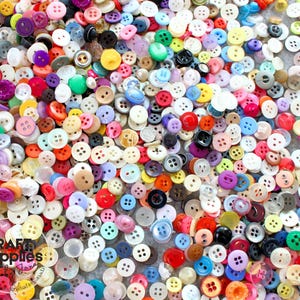 Peut inclure: Un assortiment de boutons multicolores de différentes tailles et formes. Les boutons sont de couleurs variées : rouge, bleu, vert, jaune, violet et blanc. Certains ont deux trous, d'autres quatre. L'image contient le texte "Craft Supplies Jana".