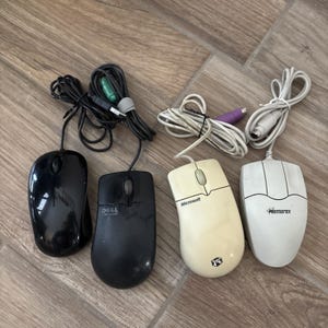 May include: Four wired computer mice with attached cables. Two mice are black, one is a Dell brand, and one is unbranded. The other two are off-white, one is a Microsoft brand with a logo, and the other is a Memorex brand. Each mouse has two buttons.