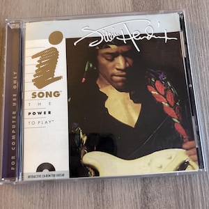 Puede incluir: Una caja de CD-ROM para el software de guitarra interactivo titulado Jimi Hendrix: The Power to Play. La portada presenta una fotografía de Jimi Hendrix tocando una guitarra eléctrica blanca, con el texto "FOR COMPUTER USE ONLY" en el lomo.