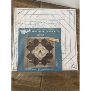 Op de afbeelding: Een doorzichtige plastic verpakking met witte papieren quilt-sjablonen met blauwe lijnen en een blauwe bijsluiter getiteld & Sew Paper Templates for Machine Piecing, met een afbeelding van een bruin en wit log cabin quiltblok.