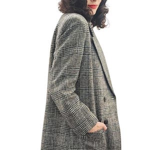 May include: A long, oversized plaid blazer in black, white, and gray, with a classic notched collar and two front pockets. The blazer is worn with a tan beret.