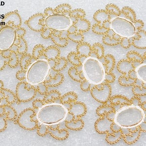 May include: Nine gold-plated brass filigree pendant stampings. Each stamping is flower-shaped with an oval center. The text on the image reads: LOT OF 9 BRASS GOLD PLATED FILIGREE PENDANT STAMPINGS 53.93mm BY 38.43mm.
