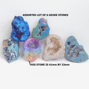 May include: An assortment of six geode stones in various colors, including blue, purple, and iridescent hues. The text "ASSORTED LOT OF 6 GEODE STONES" is displayed. One stone measures 41mm by 33mm.