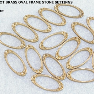 May include: A collection of fifteen brass oval frame stone settings. Each setting is approximately 1.09 inches by 0.5 inches. The frames have a decorative edge and are arranged on a light-colored surface. The text in the image reads "VINTAGE 15 PIECE LOT BRASS OVAL FRAME STONE SETTINGS".