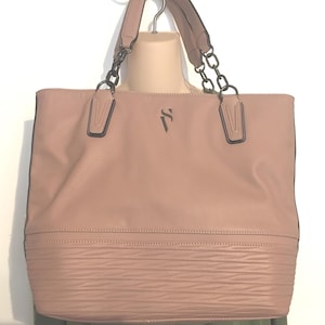 May include: A blush-colored tote bag with black chain handles and accents. The bag has a textured bottom section and a logo on the front. The bag is displayed on a mannequin.