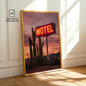 Pode incluir: Impress&atilde;o emoldurada de uma cena des&eacute;rtica ao p&ocirc;r do sol. Uma placa de n&eacute;on "MOTEL" brilha em vermelho contra um c&eacute;u crepuscular, com cactos em silhueta em primeiro plano. A imagem &eacute; emoldurada em uma borda dourada e encosta em uma parede branca.