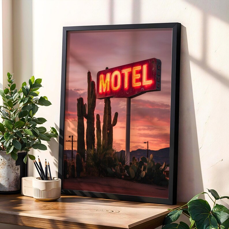 Pode incluir: Impress&atilde;o emoldurada com uma placa de motel vintage com a palavra "MOTEL" em n&eacute;on brilhante contra um c&eacute;u ao p&ocirc;r do sol. A cena inclui cactos altos e vegeta&ccedil;&atilde;o des&eacute;rtica, criando uma est&eacute;tica do sudoeste. A impress&atilde;o &eacute; exibida em uma superf&iacute;cie de madeira.
