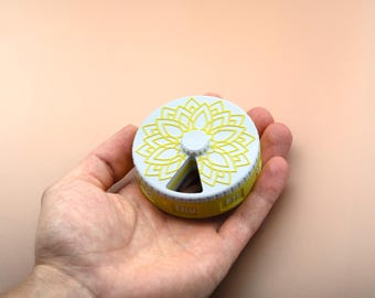 Pastillero de flores budistas: Estuche de polímero no tóxico para 7 días