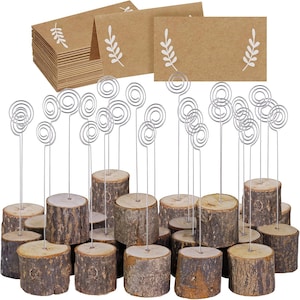 May include: A collection of rustic wooden place card holders with silver wire spirals, paired with kraft paper cards featuring a white leaf design. Ideal for weddings, parties, or events, these holders add a natural touch to table settings.