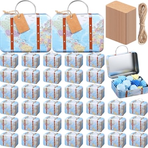 May include: A collection of miniature suitcase-shaped tins with a world map design. The tins have brown straps and handles, with a larger open tin containing blue and yellow paper decorations. Also included are brown tags and twine.