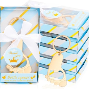 May include: Gold-colored bottle opener in the shape of a baby foot, attached to a keyring. The opener is packaged in a blue box with a white ribbon and the words "Thank you" and "Bottle opener". The boxes are stacked.