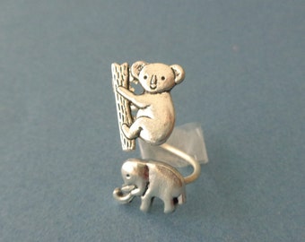 May include: A silver ring with a koala bear climbing a tree and an elephant on the other side.