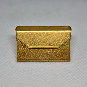 以下が含まれることがあります： ダイヤモンド柄の小さな金色の金属製のクラッチバッグ