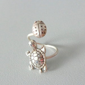 May include: Silver ring with a ladybug and a turtle design. The ring is adjustable and can be worn on any finger.