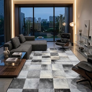 Puede incluir: Un salón moderno con un sofá seccional gris, un sillón de cuero negro y una alfombra estampada. La alfombra presenta un diseño de patchwork en tonos grises y blancos. Grandes ventanales ofrecen vistas al horizonte de la ciudad.