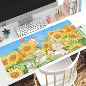 Puede incluir: Una alfombrilla de escritorio colorida con una ilustración de dibujos animados de girasoles, un conejo y niños. La alfombrilla tiene un fondo azul y presenta un cielo azul claro con nubes blancas.