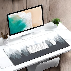 May include: A white desk with a computer monitor, a keyboard, a mouse, and a forest-themed mousepad. The mousepad has a dark gray background with a light gray forest silhouette.