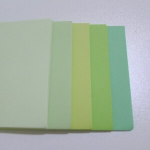 May include: Five sheets of paper in different shades of green, from light to dark.