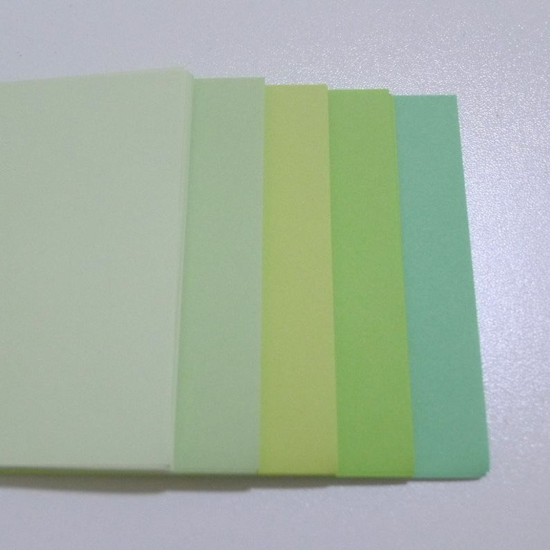 May include: Five sheets of paper in different shades of green, from light to dark.