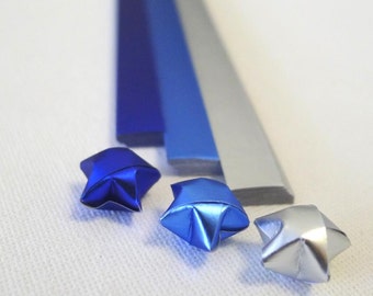 May include: Three origami stars made from metallic paper. One star is silver, and the other two are blue.