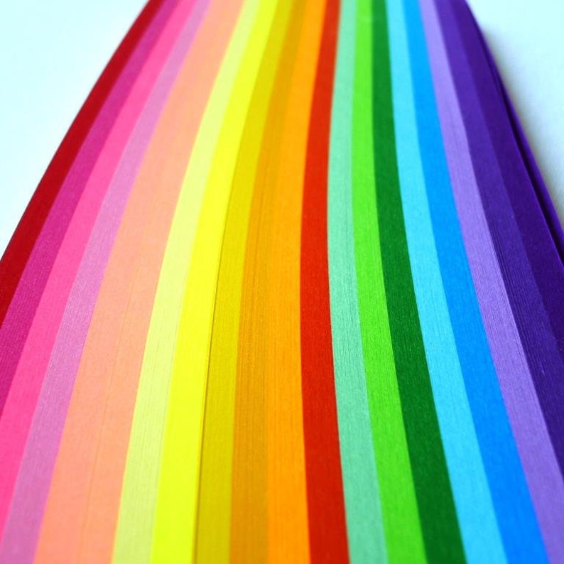 May include: A rainbow of colorful paper strips arranged in a fan shape. The colors are red, orange, yellow, green, blue, indigo, and violet.