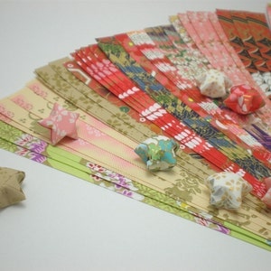 May include: A collection of colorful origami paper strips with a variety of floral and geometric patterns. Several origami stars made from the paper are scattered around the strips.