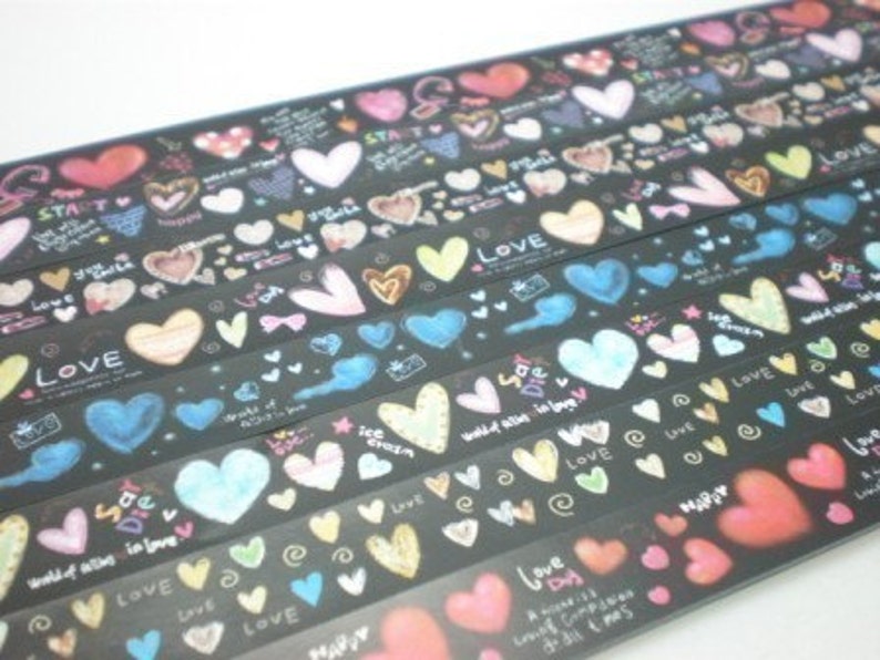 Puede incluir: Surtido de rollos de cinta washi negra y blanca con corazones coloridos y las palabras "Love", "Start", "World of love", "Ice cream", "Happy" y "Love is a lovely compass it will always point to all the best things" impresas en ellos.