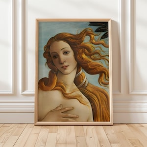 Pode incluir: Uma impressão emoldurada de "O Nascimento de Vénus" de Botticelli. A obra de arte apresenta uma mulher com longos cabelos ruivos esvoaçantes, tez pálida e expressão serena. O fundo é azul suave com um toque de folhagem.