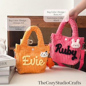 May include: Two corduroy tote bags. One is orange with "Evie" in yellow, a cat face, and a yellow handle. The other is pink with "Ruby" in black, a bunny face, and a pink handle. Both have shoulder straps.