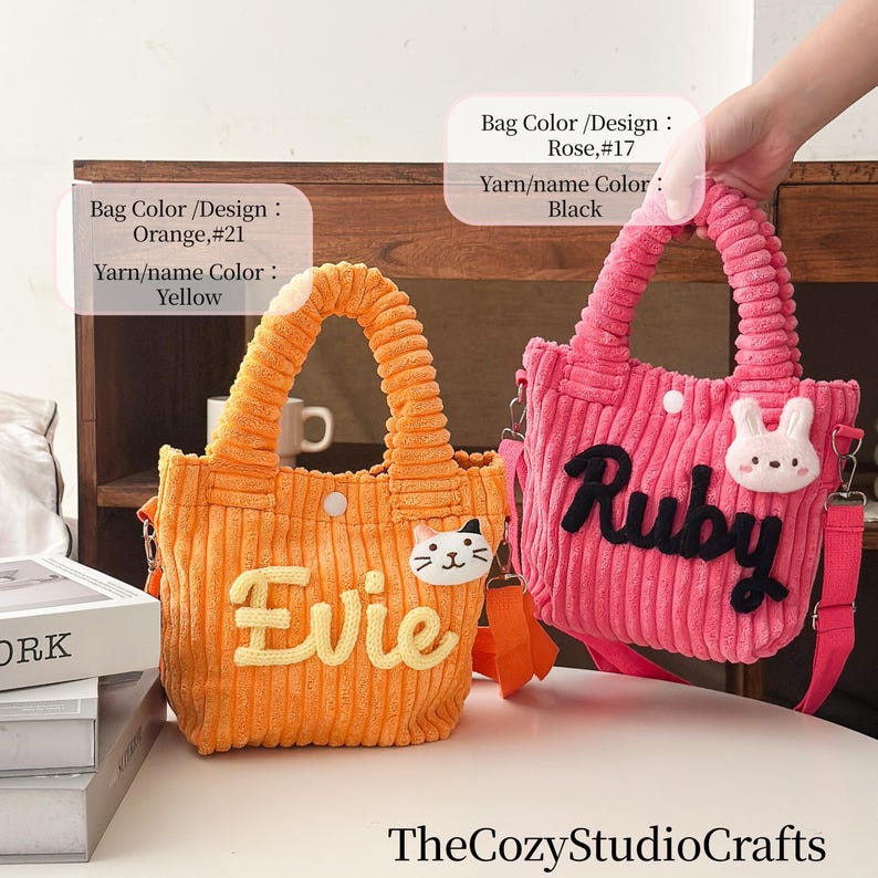 May include: Two corduroy tote bags. One is orange with "Evie" in yellow, a cat face, and a yellow handle. The other is pink with "Ruby" in black, a bunny face, and a pink handle. Both have shoulder straps.
