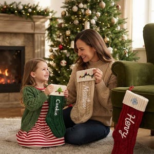 May include: Three cable-knit Christmas stockings featuring white cuffs and personalised embroidery. One green stocking is labelled Cookie, one beige stocking is labelled Matthew, and one red stocking is labelled Henry, each with a small festive icon.