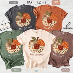 May include: Five short-sleeve t-shirts in pepper, yam, moss, ivory, and espresso colors. Each shirt features a central faux patchwork apple graphic with autumn-themed patterns and the printed name of a teacher below the apple design.