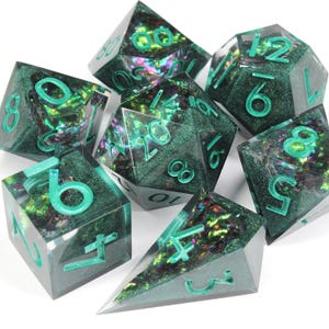 May include: A set of seven green and iridescent dice with black and white numbers. The dice are made of clear resin with a glittery finish.
