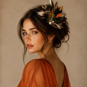 May include: A woman wearing a feather hairpiece with a variety of colors, including brown, orange, and white. The hairpiece is set against dark brown hair. The woman is wearing an orange dress. The text "kirahley kreations" is at the bottom.