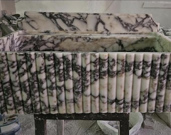May include: A rectangular stone sink featuring a white base with prominent dark purple veining. The exterior surface is characterized by a vertical fluted or ribbed texture, and the basin includes a matching stone backsplash along the rear edge.