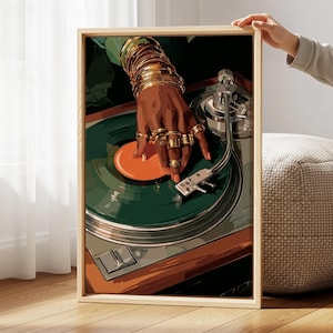 Puede incluir: Una impresi&oacute;n art&iacute;stica enmarcada representa una mano adornada con joyas de oro, colocada sobre un tocadiscos vintage. La mano es oscura, con m&uacute;ltiples anillos y pulseras. El tocadiscos presenta un disco verde con un centro naranja, sobre un fondo marr&oacute;n y plateado.