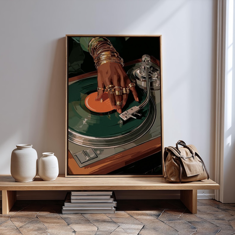 Puede incluir: Una impresi&oacute;n art&iacute;stica enmarcada representa una mano adornada con anillos y pulseras doradas, colocada sobre un disco de vinilo verde en un tocadiscos. La obra de arte tiene una est&eacute;tica retro. La impresi&oacute;n se exhibe sobre un banco de madera con jarrones blancos y una bolsa de lona.